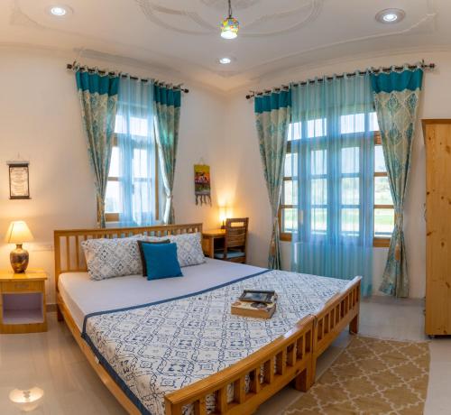 a bedroom with a large bed with blue curtains at La Maison - A Boutique Bed and Breakfast in Bīr