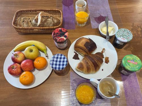 Chambre d'hôtes Les Grillons في Olemps: طاولة خشبية مع طبقين من الطعام والفواكه