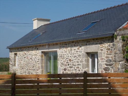 a stone house with a solar roof with a wooden fence at An ti koz in Plouguerneau