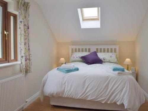 a bedroom with a white bed with purple pillows at Rosebank Cottage in Lancaster