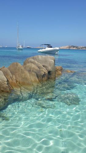 um grupo de rochas na água com um barco em sweet home la maddalena em La Maddalena