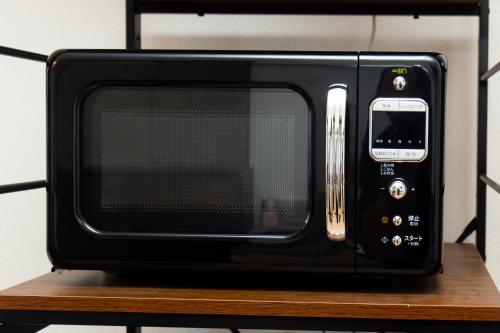a black microwave sitting on top of a wooden shelf at 唐沢ホテル Karasawa-Hotel in Tokyo