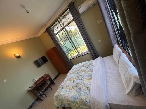 ein Schlafzimmer mit einem Bett und einem großen Fenster in der Unterkunft PHYLLEN HOTEL in Tanga