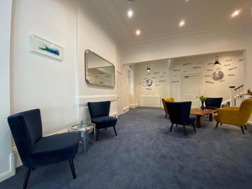 a waiting room with chairs and a table and a mirror at Rooms At Babbacombe in Torquay