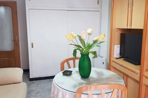 a green vase with white flowers on a table at Apartamento Armonía:céntrico, tranquilo y acogedor in Elda