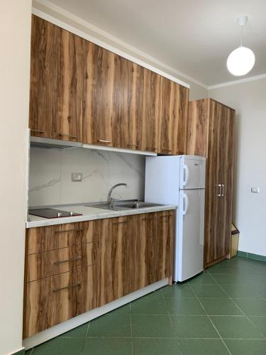 a kitchen with wooden cabinets and a white refrigerator at Eri Apartments 4 in Shëngjin