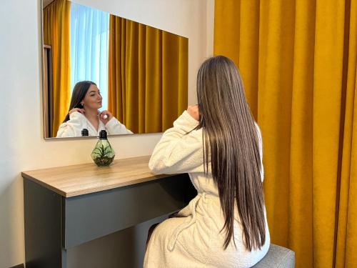 Una donna seduta alla scrivania di fronte a uno specchio di Arena Apart - Hotel a Polyana