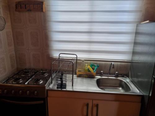 a kitchen with a sink and a stove and a window at Cabaña Beatriz in Coñaripe