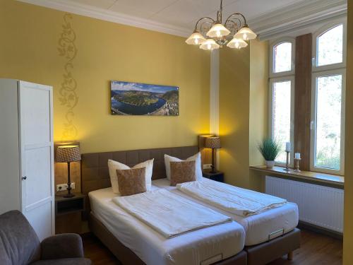 um quarto com uma cama e um lustre em Haus Hohenzollern & Haus 'Ambiente em Bad Bertrich