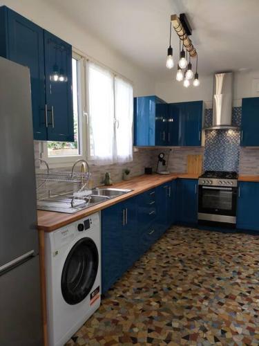 a kitchen with blue cabinets and a washing machine at maison tout confort avec piscine in Saint-Benoît-du-Sault