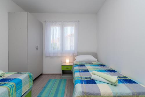 a small bedroom with two beds and a window at Apartmani Lejla in Poljica