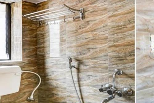 a shower in a bathroom with a stone wall at Hotel Manasi INN in Satara