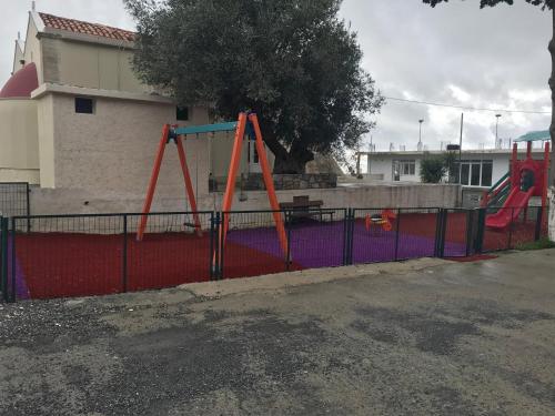 a playground with a swing set on a fence at Drosostalida in Áno Sími