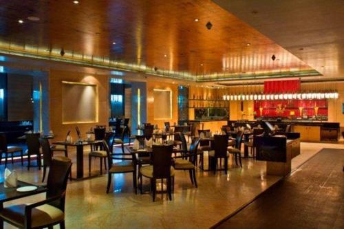 a restaurant with tables and chairs and a bar at Radisson Blu Marina Hotel Connaught Place in New Delhi
