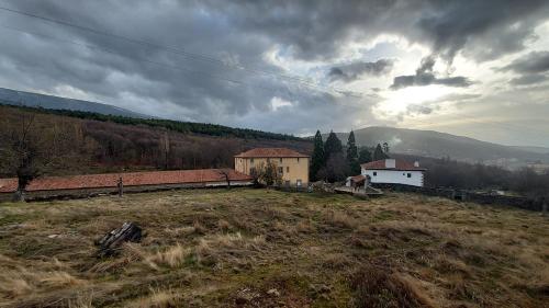 a field with a house on a hill with a cloudy sky at La Covatilla III in La Hoya