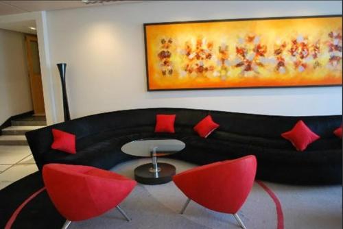 a living room with a black couch and red chairs at Radisson Blu Marina Hotel Connaught Place in New Delhi