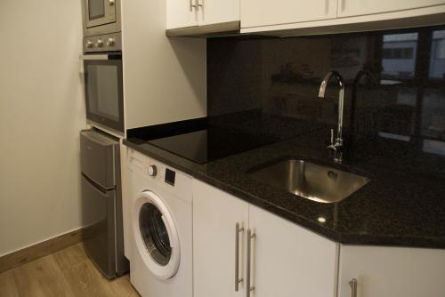 a kitchen with a sink and a washing machine at Apartamentos turisticos HAZ AMIGO in Muxia