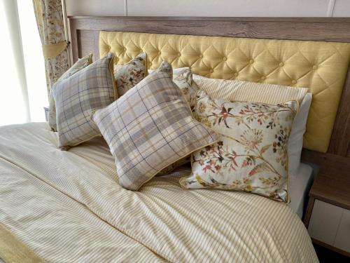 a bed with a bunch of pillows on it at Puddleducks, Dog Friendly Hot Tub Lodge in South Cerney