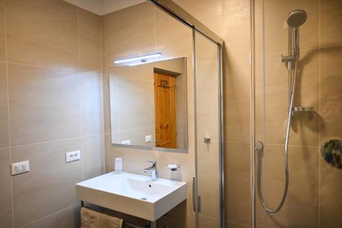 a bathroom with a sink and a shower with a mirror at Garni Meinrad in Ora/Auer