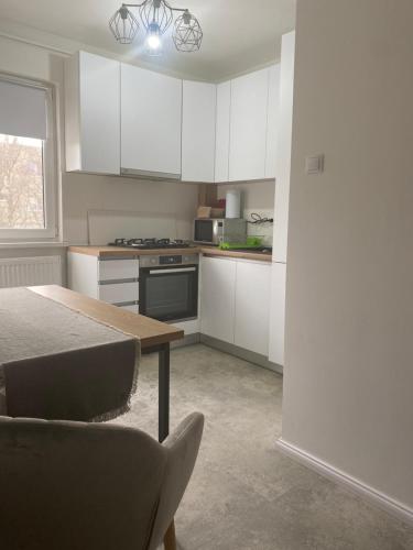 a kitchen with white cabinets and a table at Astra 1bedroom in Braşov