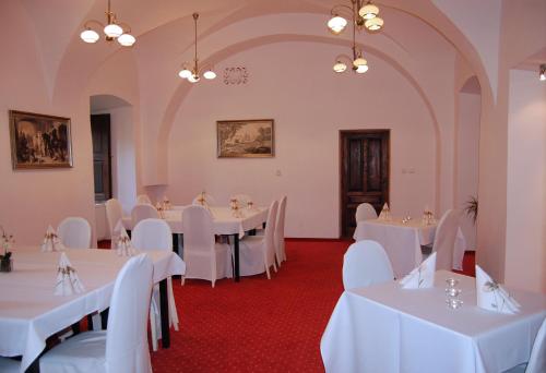un salón de banquetes con mesas y sillas blancas en Hotel Zámok Topoľčianky, en Topoľčianky