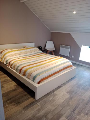 - une chambre avec un grand lit et une couette à rayures dans l'établissement Pounette, appartement T2, centre thermes Luxeuil, à Luxeuil-les-Bains
