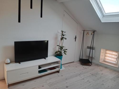 a living room with a flat screen tv on a white cabinet at Pounette, appartement T2, centre thermes Luxeuil in Luxeuil-les-Bains