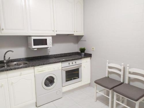 a kitchen with white cabinets and a sink and a dishwasher at Apartamento en el centro de Laredo Menendez Pelayo 17 in Laredo