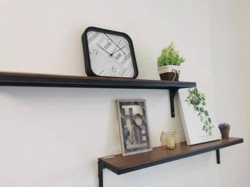 a shelf with a clock and plants on it at Continew Residence by HomeBrickz in Kuala Lumpur