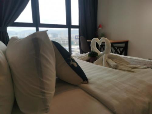 a bed with white sheets and a heart shaped pillow at Continew Residence by HomeBrickz in Kuala Lumpur