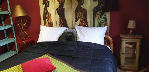 a bed with a black comforter and white pillows at Chambres Du Petit Bonheur in Biscarrosse