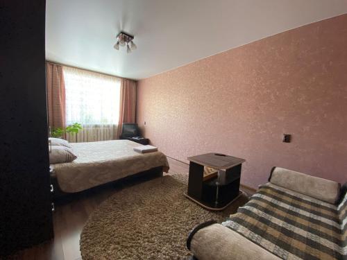 Habitación con 2 camas, sofá y mesa. en Апартаменты, en Kineshma