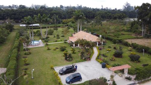 an aerial view of a house with two cars parked in a yard at Hermosa Cabana con bonito Jardin y piscina en la Mesa de los Santos in Los Curos