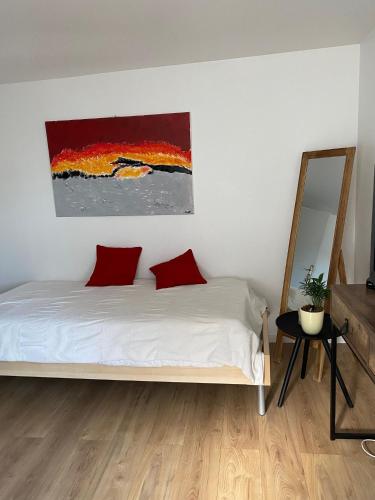 a bedroom with a bed with red pillows and a painting at Aux portes du Val d'Amour in Sellières