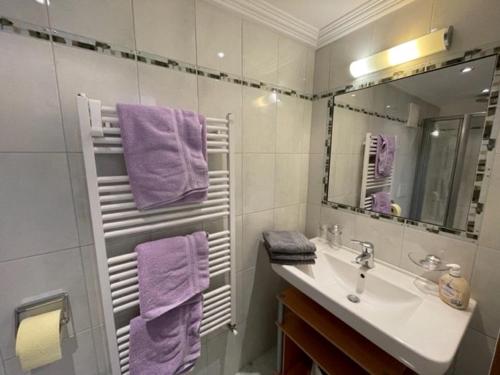 a bathroom with a sink and a mirror and purple towels at Gästehaus Garber in Stumm