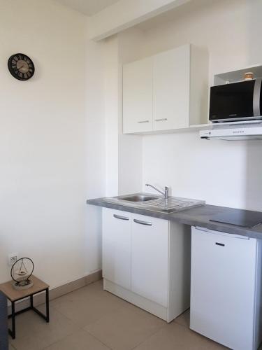 a white kitchen with a sink and a microwave at Appartement T2 Très bon standing vue mer in Sainte-Clotilde