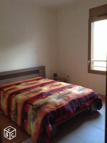 - une chambre avec un lit et une couverture colorée dans l'établissement Appartement T2 Très bon standing vue mer, à Sainte-Clotilde