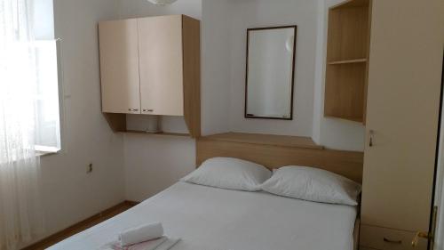 a bedroom with a white bed and a mirror at House Lopin in Žuljana