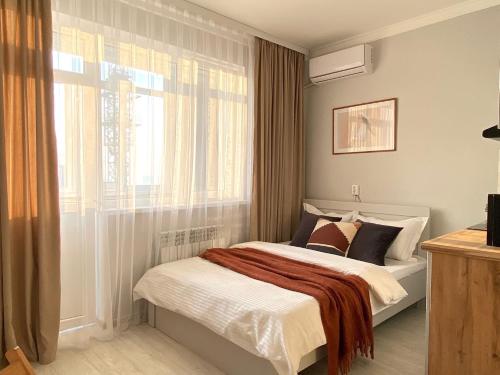 um quarto com uma cama e uma janela em Skandi em Almaty