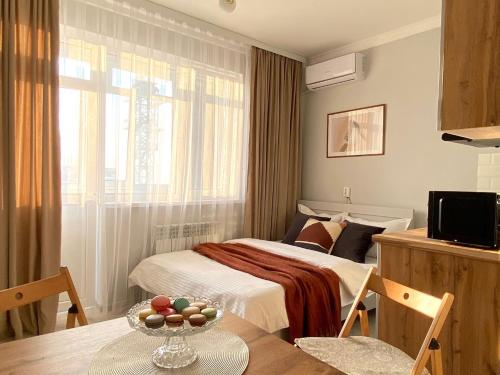 um quarto com uma cama e uma mesa com uma tigela de fruta em Skandi em Almaty