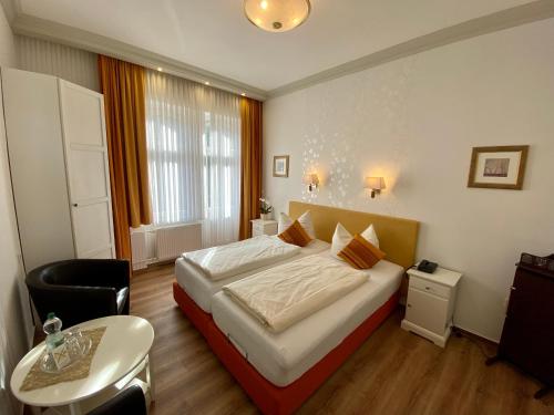 a hotel room with a bed and a chair and a table at Haus Hohenzollern & Haus 'Ambiente in Bad Bertrich