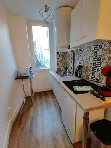 une cuisine avec des armoires blanches et un plancher en bois dans l'établissement Le Comte est bon, quartier Antiquaires, à Dijon