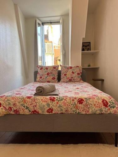 d'un lit avec une couette et des oreillers à fleurs, ainsi que d'une fenêtre. dans l'établissement Le Comte est bon, quartier Antiquaires, à Dijon