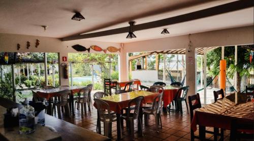 un restaurante con mesas, sillas y ventanas en Pousada Sol Dourado, en Jijoca de Jericoacoara