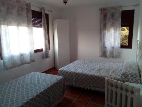 a bedroom with two beds and two windows at CASA RURAL El Paso in Prado del Rey