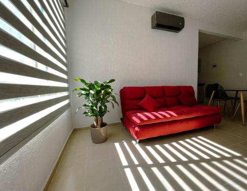 Sofá rojo sentado en una habitación con ventana en Depa Xcalacoco, Playa Del Carmen en Playa del Carmen