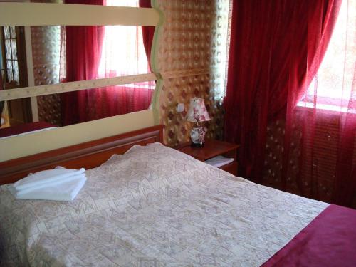 a bedroom with a bed with red curtains and a mirror at Ust-Kamenogorsk Hotel in Ustʼ-Kamenogorsk