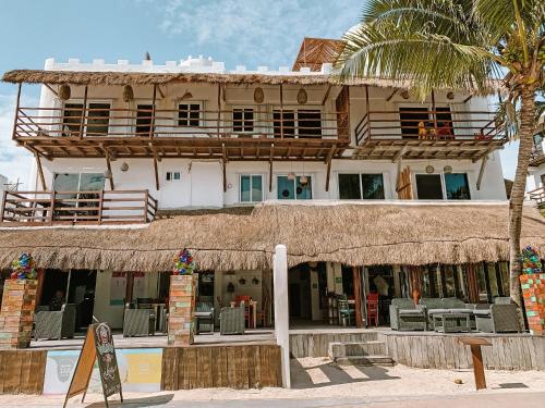 a building on the beach with a straw roof at El Fuerte Beach Apartments in Mahahual