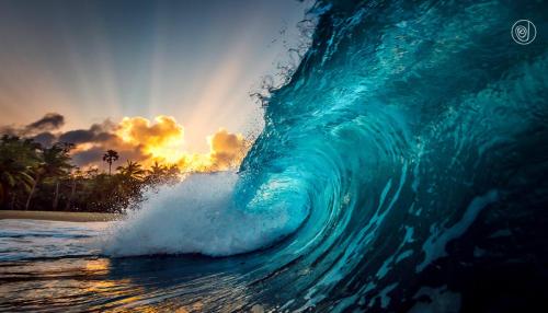 a large wave in the ocean with a sunset in the background at Residencial Mañanero in Cabarete