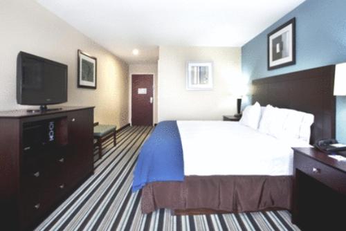 a hotel room with a bed and a flat screen tv at Holiday Inn Express Hotel & Suites Baton Rouge -Port Allen by IHG in Port Allen